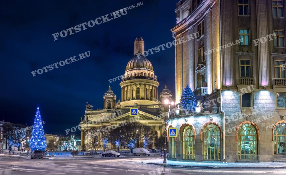На фотографии изображен Исаакиевский собор в Санкт-Петербурге ночью зимой. Здание украшено новогодними огнями, а на переднем плане видны праздничные елки. Фото идеально подходит для использования в туристических и праздничных буклетах, открытках и иллюстрациях в СМИ.